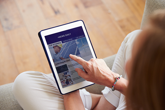 Woman Looking At News App On Digital Tablet